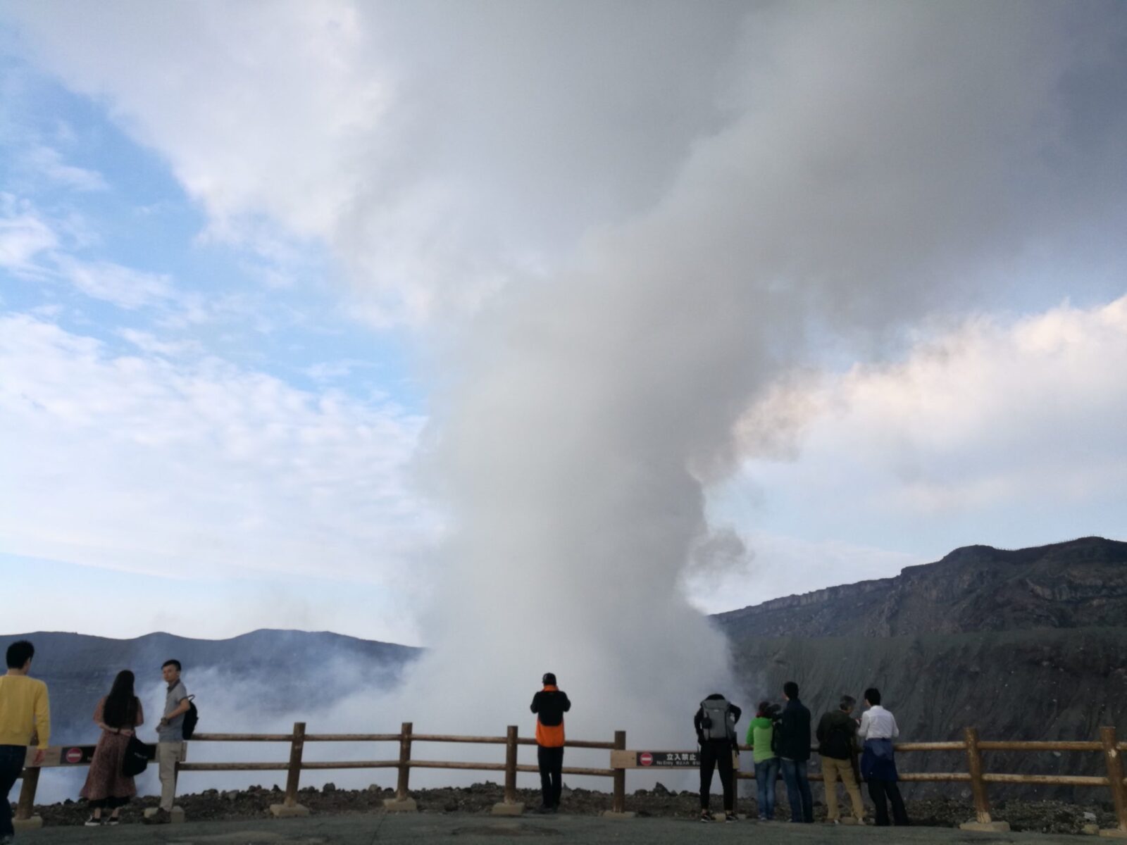 people standing next to smoking crater Mount Aso volcano crater tour Nakadake volcano