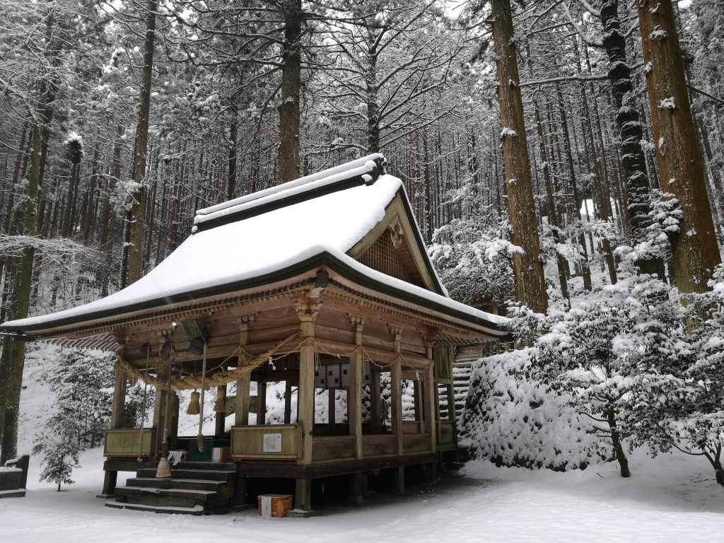 shrine building with a snowy roof in forest