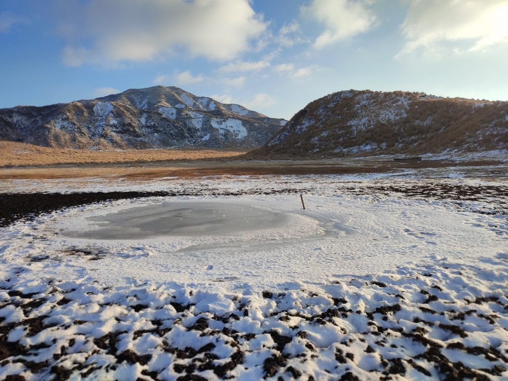 frozen pond on aso grasslands at kusasenri in japan