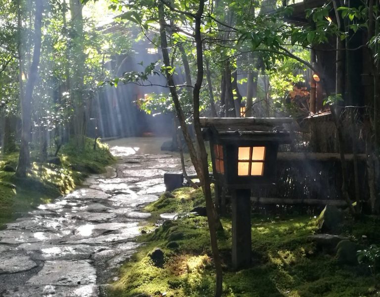 sunlight through leaves stone path and japanese lantern Noshiyu onsen Kurokawa onsen Aso Kyushu Japan